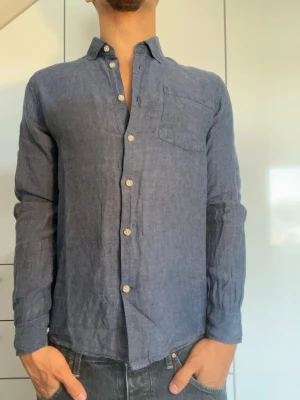 Blå linneskjorta från Hampton Republic - Blå skjorta i 100% Linne från Hampton Republic. Strl S. Inga defekter. Modellen är 178 cm och väger 77 kg. Hör gärna av dig vid frågor!