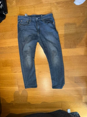Blå Levi's 502 straight/slim  jeans W33 L32 - Säljer ett par klassiska blå Levi's 502 straight/slim jeans med fem fickor och dragkedjegylf. Jeansen har en lätt tvättad look och raka ben. Perfekta för en avslappnad stil och passar till det mesta. Materialet är bomullsdenim. Har även sytt upp dem 1 cm W33 L32