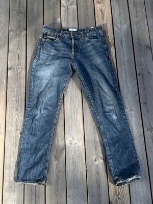 Jack & Jones Chris - Snygga blå jeans med typ guldiga/bruna sömmar, stl 31/34, hål i båda fickorna fram