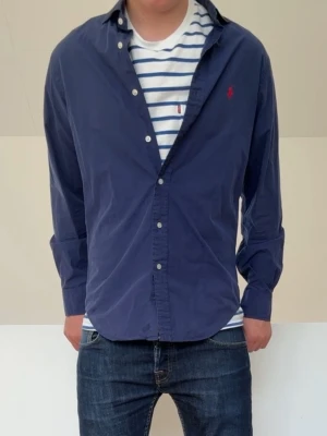 Mörkblå Ralph Lauren skjorta - Mörkblå Ralph Lauren skjorta i mycket bra skick och sitter i strl M! Hör gärna av er vid frågor elr funderingar!!