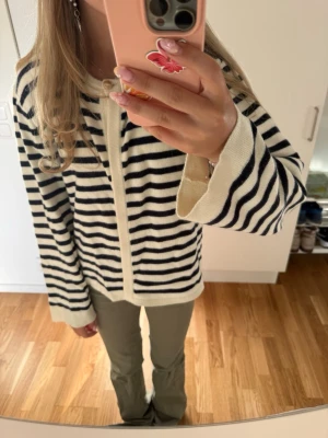 Randig kofta med knappar - Säljer en krämvit och marinblå randig kofta med knäppning framtill. Koftan har långa ärmar, avslappnad passform och ribbade kanter. Perfekt för lager på lager och ger en klassisk look till din outfit. Den är ifrån Gina och använd två till tre gånger 💕💕💕