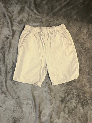 Beiga shorts från Kappahl med snörning - Säljer ett par beiga shorts från Kappahl i storlek 152. De har elastisk midja med snörning och två sidofickor. Perfekta för varma dagar och har en avslappnad passform. Materialet känns lätt och luftigt. Vid frågor hör av er och priset kan alltid diskuteras 