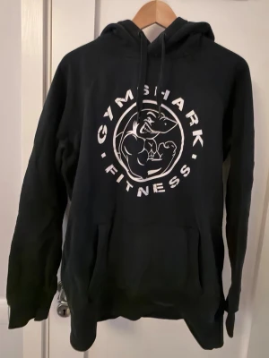 Svart Gymshark hoodie med tryck - Svart hoodie från Gymshark med legacy tryck. Perfekt för gymmet eller chill dagar. 