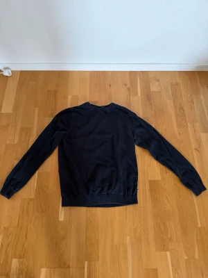 Mörkblå tröja från Jack & Jones - En stilren mörkblå tröja från Jack & Jones med rund halsringning och ribbade muddar vid ärmslut och nederkant. Perfekt för dig som gillar en enkel och klassisk look. Materialet känns mjukt och bekvämt mot huden.