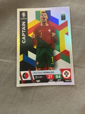 Samlarbild Cristiano Ronaldo EURO 2024 - Säljer en färgglad samlarbild med Cristiano Ronaldo från EURO 2024. Kortet har holografisk yta, texten CAPTAIN och visar Ronaldo i Portugals landslagströja. Perfekt för dig som gillar fotboll och samlarbilder.