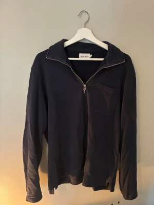 Mörkblå halvzip från East West - Mörkblå långärmad tröja från East West med halvzip och bröstficka. Tröjan har en avslappnad passform och mjukt material, perfekt för en chill och stilren look. Dragkedjan framtill gör det enkelt att justera stilen. Hör av er vid frågor - vid snabba köp kan priset sänkas🔥
