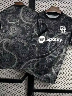 Svart paisleymönstrad Barca t-shirt - Snygg svart t-shirt från FC Barcelona med vitt paisleymönster och klubbmärke på bröstet. Spotify-logga tryckt framtill. Rund halsringning och korta ärmar. Perfekt för dig som vill sticka ut med stilren fotbollsinspiration.