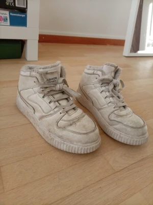 Vita high top sneakers Fashion Sport - Säljer ett par vita high top sneakers från Fashion Sport. Skorna har en chunky sula, snörning och mjukt foder runt kanten. Tillverkade i syntetmaterial med detaljer i samma ton. Perfekta för dig som gillar en sportig och trendig look. Ganska använda dock men funkar utmärkt än 