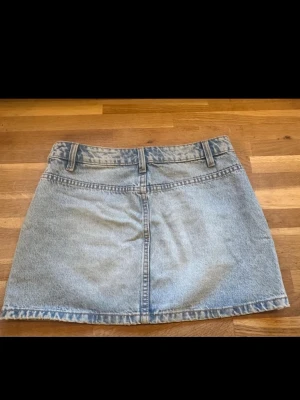 Jeanskjol - Säljer en klassisk ljusblå jeanskjol i kort modell. Kjolen har bälteshällor, två bakfickor och en enkel design som passar till det mesta. Perfekt för dig som gillar en avslappnad och trendig stil.