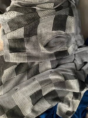 Colesice shorts set  - Säljer en grå stickad tröja med rutigt mönster i olika nyanser av grått och svart. Tröjan har en avslappnad passform och är tillverkad i ett mjukt, stickat material. Perfekt för dig som gillar en stilren och modern look.