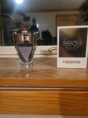 Paco Rabanne Invictus parfym - En cool parfym från Paco Rabanne, Invictus, med en unik troféformad flaska i glas och silverfärgade detaljer. Doften har en fräsch och sportig känsla och flaskan har en lila tonad vätska. Kommer med originalkartong.