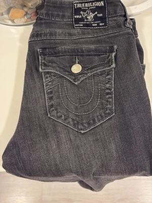 True Religion grå bootcut jeans - Snygga grå jeans från True Religion, modell Becca, Bootcut. Jätte fina! Köpta här på plick men dem passade tyvärr inte mig! Lite slitna längst ner.