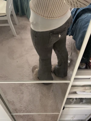 Grå bootcut jeans från True Religion - Säljer ett par grå bootcut jeans från True Religion med klassiska kontrastsömmar och ikonisk fickdetalj bak. Jeansen har låg midja och är tillverkade i ett stretchigt denimtyg som sitter snyggt. Pris går att diskutera💘Hör gärna av er om ni vill ha fler bilder💕Köpte för 1299💕