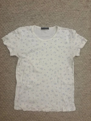 Vit t-shirt med blått nallemönster - Supersöt vit t-shirt från Brandy Melville med små blå nallar och rosetter🐻💙