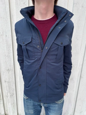 J.Lindeberg Bailey Fieldjacket - En sjukt clean fieldjacket med ett nypris på 3500kr! Perfekt till våren! Modellen är 177 cm. Hör av dig vid frågor!