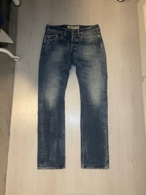 Blå raka jeans från Replay - Säljer ett par blå raka jeans från Replay med slitna detaljer och ljus stonewash. Klassisk femficksmodell med knappgylf och kontrastsömmar. Perfekta för dig som försöker utveckla stilen!, Totallängd; 108cm, Midja; 41cm, W32/L34, passa på att köpa flera plagg så får du en bundle rabatt! 