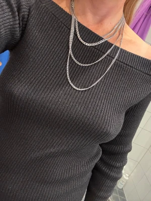 Svart off shoulder stickad tröja stl M - Säljer en svart ribbstickad off shoulder-tröja med långa ärmar. Tröjan har en tight passform och bred urringning som sitter snyggt över axlarna. Perfekt för dig som vill ha en enkel men stilren stickad topp till garderoben.