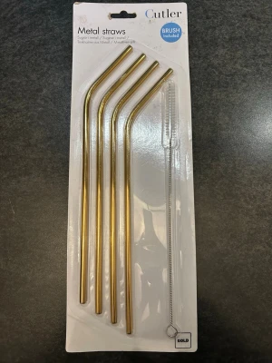 Ett set med fyra guldfärgade metall sugrör  - Ett set med fyra guldfärgade metall sugrör från Cutler. Sugrören är böjda och kommer med en rengöringsborste. Perfekt för dig som vill ha ett hållbart alternativ till plast. 