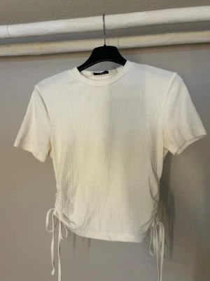 Vit ribbad crop top med knytband - Vit ribbad top med korta ärmar, från NA-KD i storlek XS