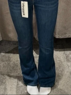 Mörkblå lågmidjade bootcut jeans från Kappahl - Säljer ett par mörkblå bootcut jeans från Kappahl med klassisk femficksmodell och låg midja. Jeansen har en lätt utsvängd passform nedtill och är tillverkade i denim med lite stretch för extra komfort. Perfekta till sneakers eller boots.