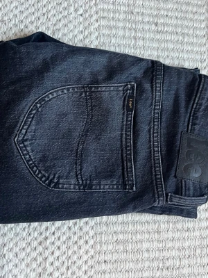 Mörkgrå lee jeans i nyskick! - Säljer dessa riktigt snygga och sköna mörkgrå Lee jeans i modellen West, storleken är 30/32 och de är i nästintill nyskick då de knappt blivit använda, kvitto finns köptes för några månader sen i butik! Nypris var typ 1200 därför är 429 sjukt bra!
