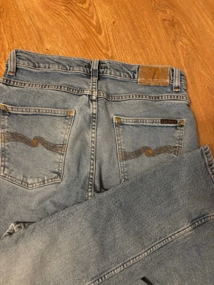 Nudie jeans - Säljer ett par ljusblåa nudie jeans i mycket fint skick! De är i storlek W30 L32!                  Mått (se sista bilden):                                           A=40cm. B=77cm. C=100cm. D= 15cm.           Bara att hör av sig vid funderingar!