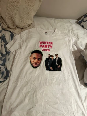Vit t-shirt Winter Party 2025 - Vit t-shirt med tryck i rosa och svart text 'WINTER PARTY 2025' Ike och storstadspojkarna på tröjan går ej att få tag på då den kastades från cen till mig ifrån storstadspojkarna pris kan diskuteras 