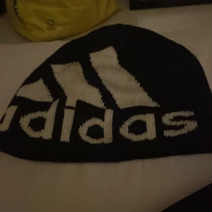 Klädpaket pojke storlek 140 - Säljer en svart mössa från Adidas med stor vit logga och text framtill. Klassisk modell som sitter skönt på huvudet och passar perfekt till kalla dagar.Även en piké kortärmad orange plus en långärmad underställ tröja från five.