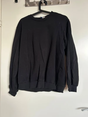 Svart sweatshirt från Monki - En enkel svart sweatshirt från HM med rund halsringning och ribbade muddar vid ärmslut och nederkant. Tröjan är tillverkad i mjukt bomullsmaterial och har en avslappnad passform som passar perfekt till jeans eller mjukisbyxor.