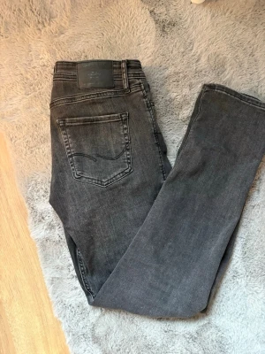 Grå Jack&Jones jeans w30 l32 - Säljer ett par snygga grå Jack and Jones jeans i modellen Slim glenn. Har endast använts ett fåtal gånger. Jag är 180 cm lång och den sitter bra. Hör av er vid minsta fundering!