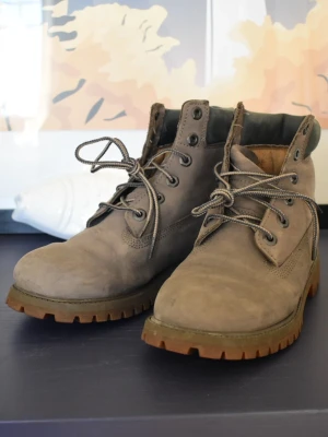 Timberland kängor i mocka - Snygga kängor från Timberland i mocka med grov sula och klassisk snörning. Kängorna har vadderad kant upptill och robust design som passar perfekt till streetwear. Timberland-loggan är präglad på sidan.