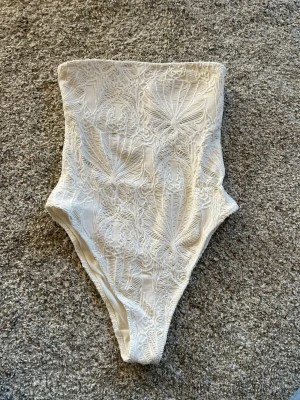 Vit spetsbody med hög midja - Säljer en superfin vit body med spetsdetaljer. Perfekt till fest och i sommar, har använt 1 gång