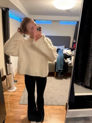 Vit stickad tröja från arket  - Säljer en vit stickad tröja med breda ärmar och dekorativa stickade detaljer längs ärmarna. Tröjan har en lös passform och rund halsringning, perfekt för att skapa en avslappnad och trendig look. Materialet ser ut att vara mjukt och fluffigt.