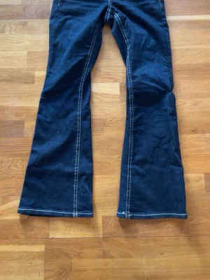 Mörkblå bootcutjeans från Gina Tricot - Snygga mörkblå bootcutjeans från Gina Tricot med kontrastsömmar och klassisk femficksdesign. Andvända endast en gång. Jeansen har dragkedjegylf och markerade sömmar längs benen för en trendig look. Perfekta för dig som gillar mörka och super snygga jeans😍