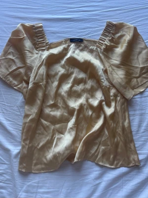 Ljusgul satinblus från Stockh LM - Snygg ljusgul blus i satin från Stockh LM. Blusen har korta armar med rynkade detaljer vid axlarna 