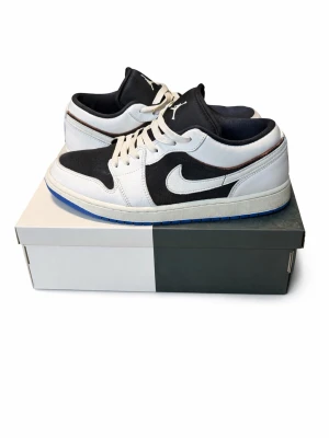 Air Jordan 1 Low svart/vit - Snygga Air Jordan 1 Low sneakers i svart och vitt o cg en blå undersida. I väldigt bra skick då jag har använt den ett få tal gånger. Skickar inom 24h. Fråga gärna om du har några frågor eller funderingar!