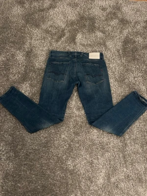 Blå jeans från replay med snygga detaljer  - Snygga blå jeans från replay med nice detaljer. Säljer eftersom dom blivit för små för mig. Perfekta för dig som gillar en stilren och tidlös look. Storlek ser ni på bilden. 31 W 32 L. Nypris- 1999 || Mitt pris- 500