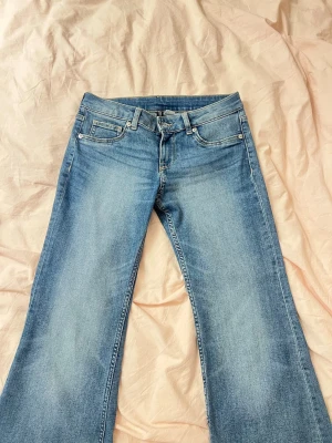 Blå bootcut jeans med utsvängda ben - Säljer ett par ljusblå bootcut jeans med klassisk femficksmodell och utsvängda ben. Jeansen har normal midja och är tillverkade i mjukt denimtyg. Perfekta för dig som gillar retrovibbar och en avslappnad look.