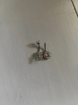 2 stycken navelpiercingar - Den med blå sten är från piercingkungen och är i nyskick, den rosa är från glitter och har tappat lite färg🩷
