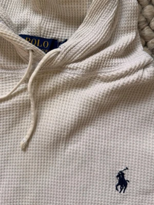 Vit hoodie från Polo Ralph Lauren🙌 - Säljer en vit hoodie från Polo Ralph Lauren i mjukt, strukturerat bomullstyg med dragsko i huvan och den klassiska mörkblå loggan broderad på bröstet. Perfekt för en chill och stilren look.