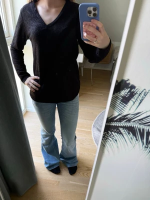 Svart V-ringad långärmad tröja - Säljer en svart långärmad tröja med V-ringning. Tröjan har en enkel och stilren design, mjukt material och en något lös passform. Perfekt att matcha med jeans eller kjol för en avslappnad look.