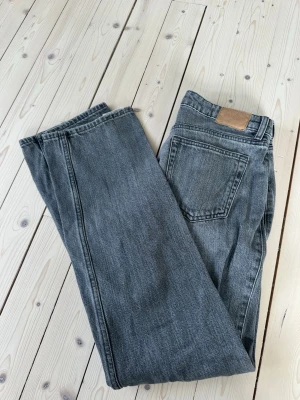Grå lågmidjade raka jeans med vintagekänsla - Säljer ett par lågmidjade grå jeans med rak passform och klassisk femficksdesign. Från weekday i modellen ”arrow” i storleken w27 l32. Jeansen har en snygg vintagekänsla och är tillverkade i denim. Perfekta för dig som gillar en avslappnad och tidlös stil. Nypris 590kr. Mycket fint skick!