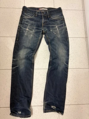 Levi's 511 blå slitna jeans - Säljer ett par blå Levi's 511 jeans med snygga slitningar och tvättade detaljer. Storlek w29 L32 sitter lite bootcut.