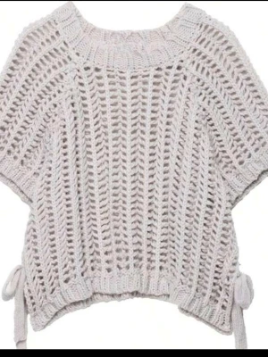 Beige virkad stickad topp - Säljer en , kortärmad stickad topp med virkat mönster och bred ribbad halsringning. Toppen har knytband i sidorna och en luftig, oversized passform som ger en avslappnad vibe. Perfekt att styla över ett linne eller t-shirt. Inte använt den är helt ny