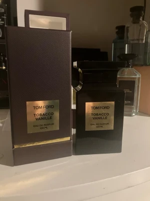 Tom Ford Tobacco Vanille Eau de Parfum - Tom Ford Tobacco Vanille Eau de Parfum 100 ml. Flaskan är svart med guldiga detaljer och har en lyxig, fyrkantig design. Kommer med originalkartong i mörk lila nyans och guldplatta. Perfekt för dig som gillar exklusiva och djupa dofter. Full presentation + kvitto finns nästan helt full c 97 ml 