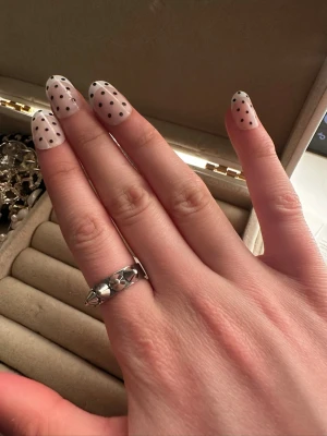 Silvrig ring med nitar - Cool silvrig ring med markerade nitar runt hela bandet. Ringen har en edgy och modern design som sticker ut och passar perfekt för dig som gillar att addera en tuff detalj till din stil. Tillverkad i metall med blank finish.