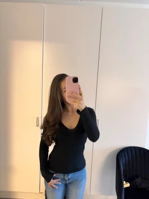 Svart långärmad v-ringad topp - Säljer en svart långärmad topp med v-ringning. Toppen har en slim passform och är enkel att matcha med olika outfits. Perfekt för dig som gillar stilrena och klassiska plagg.