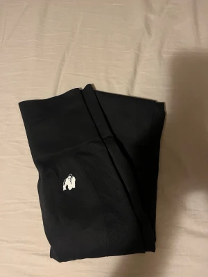 Svarta leggings från Gorilla Wear - Snygga svarta leggings från Gorilla Wear med hög midja, scrunch vid rumpan och stretchigt material. Diskret logga med gorilla på benet. Perfekta för träning eller chill. Tight passform som framhäver benen och ger en sportig look. Endast använd enstaka gång. 