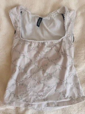 Rosa linnetopp🪷💌 - Supersöt ljus linnetopp från Hm med diskret blommigt mönster och spetsdetaljer vid urringningen. Toppen har breda axelband och fyrkantig ringning, perfekt för en fräsch och romantisk look.
