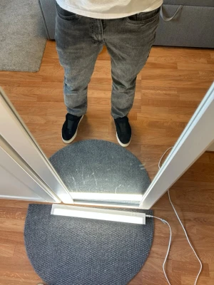 Grå tvättade raka jeans - Säljer ett par grå tvättade jeans med rak passform och klassisk femficksdesign. Jeansen har normal midja och är tillverkade i ett mjukt denimtyg som ger en avslappnad look. Perfekta för dig som gillar en stilren och enkel vibe.